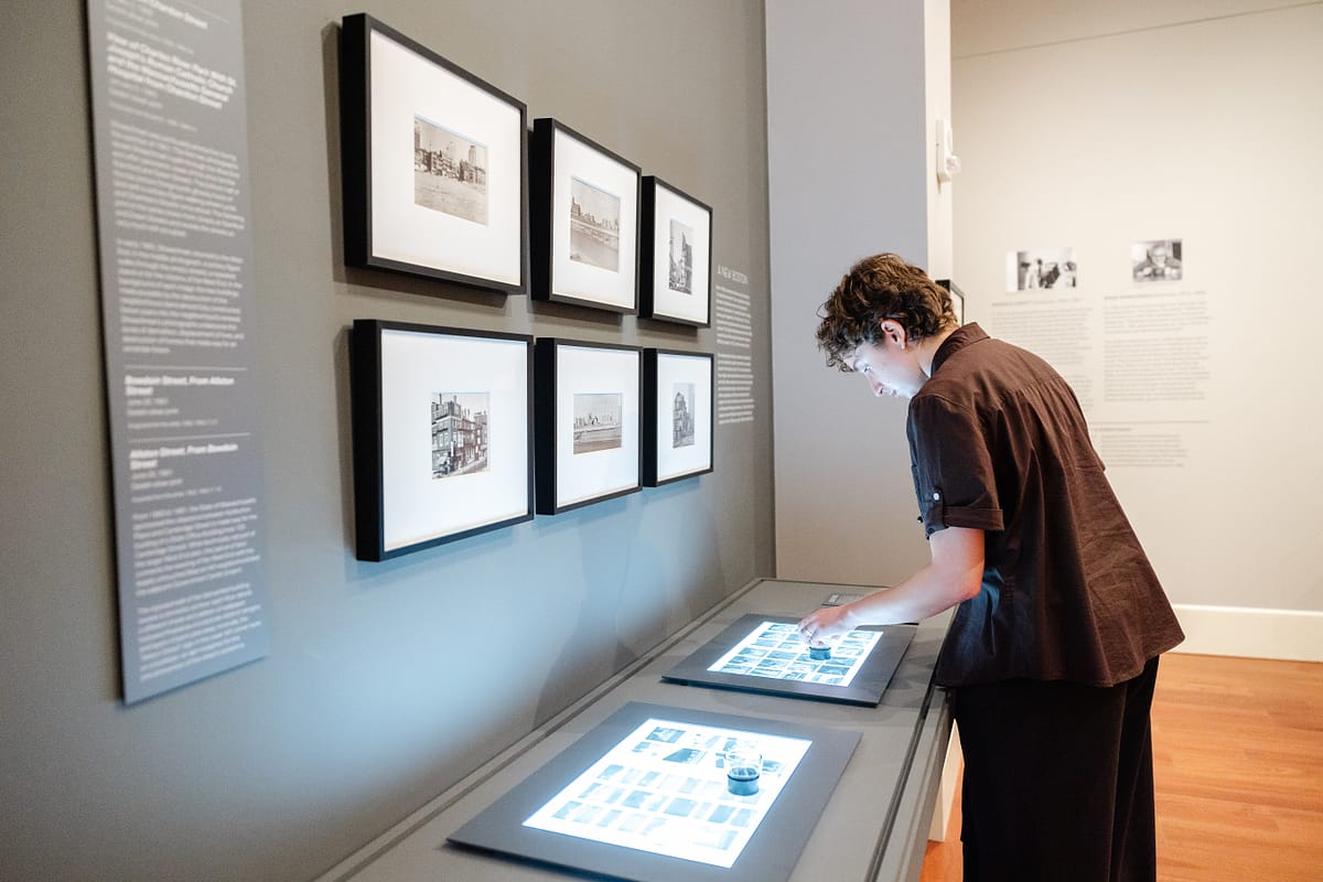 Person viewing photograph contact sheets in the Athenaeum's new exhibition gallery.