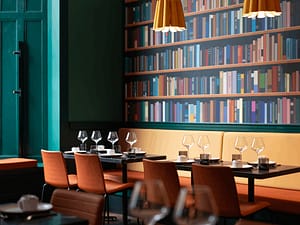 Folio Bistro interior with tables set and a wallpaper with images of books imprinted in the background.